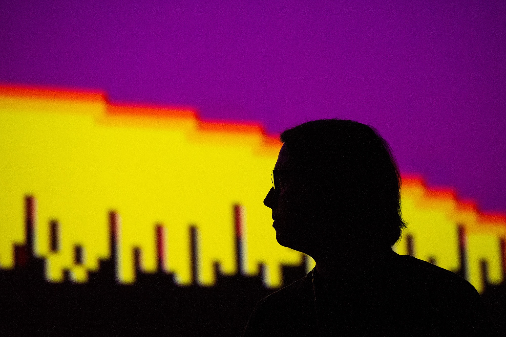 A photograph of Wiley Wiggins in front of a projection of a videogame