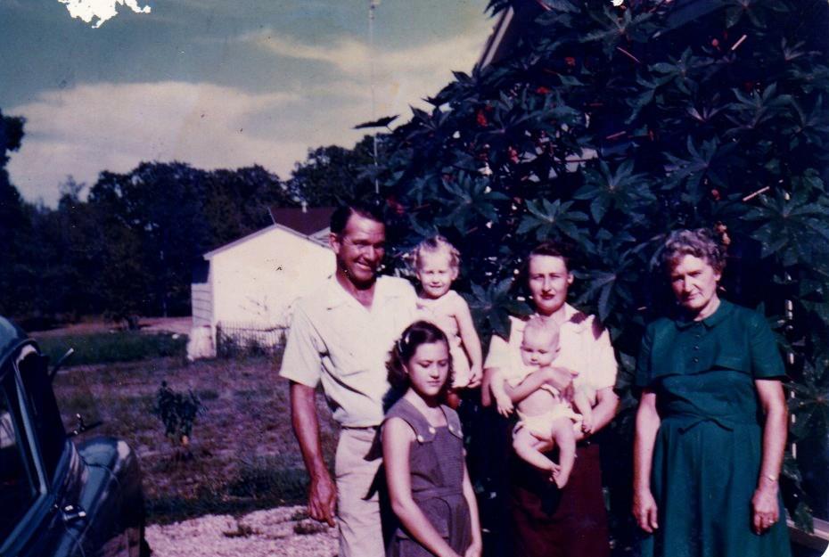 An early color photograph of a family outdoors, the eldest child has downturned eyes