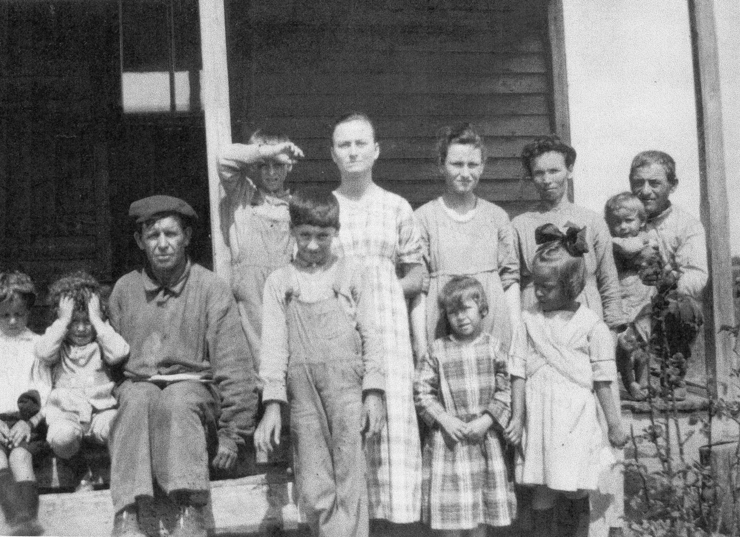 Peter Paul Fridel and family, dusty, in old clothes, assembled on a porch