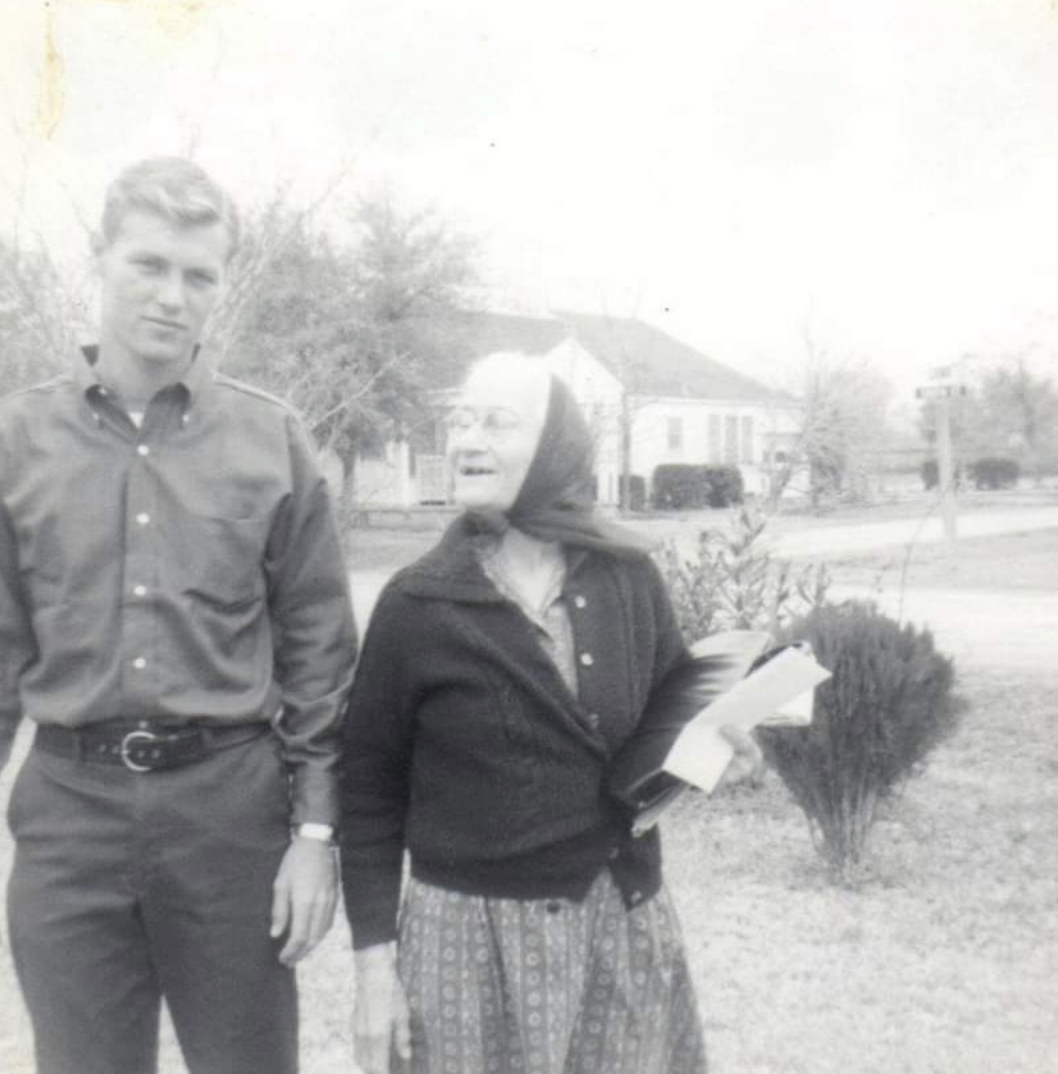 a young man and an old woman, black and white, her face is turned towards the sun, smiling, missing teeth